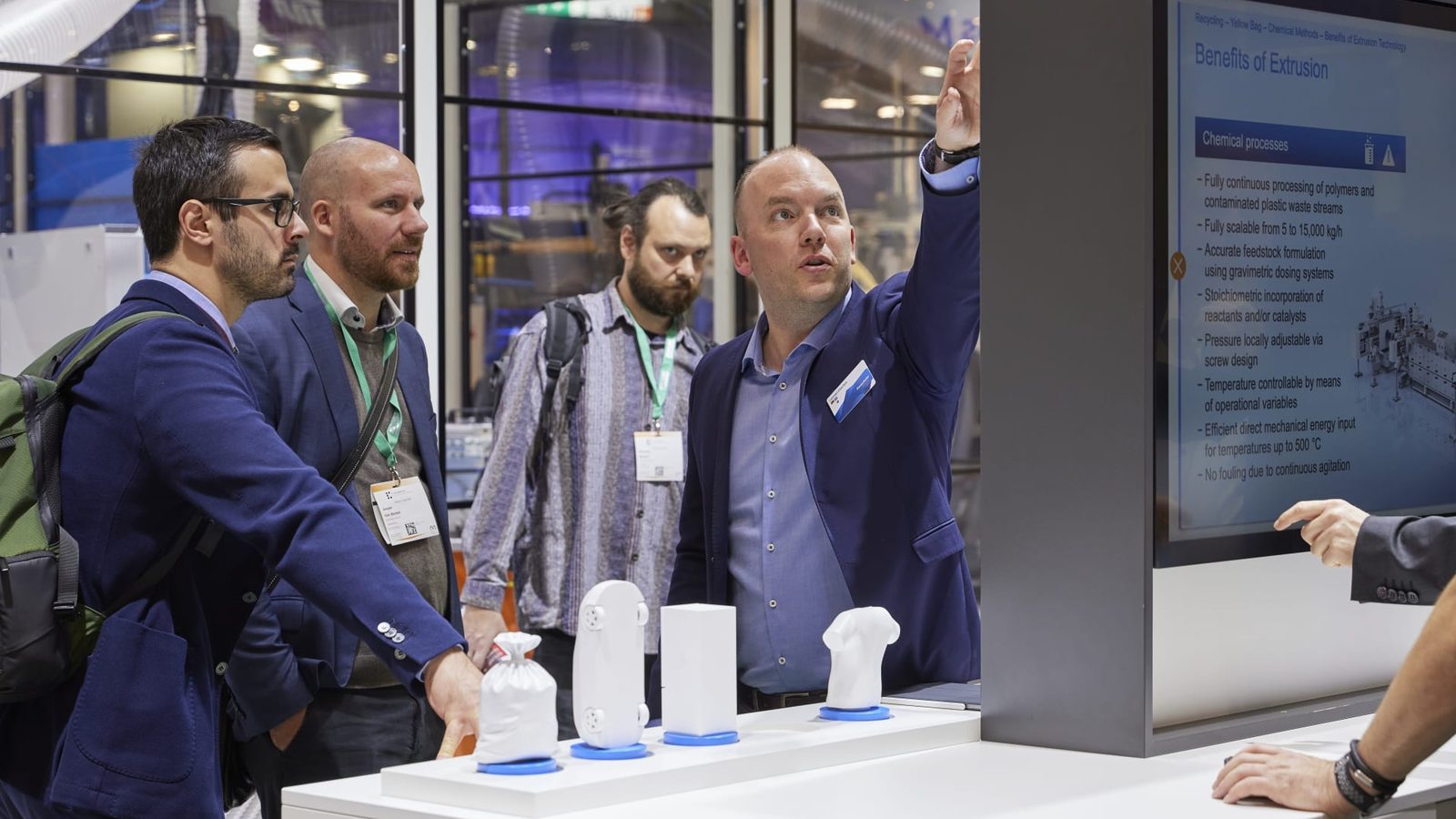 Besucher vor einem Exponat mit Bildschirm auf dem Messestand von KraussMaffei