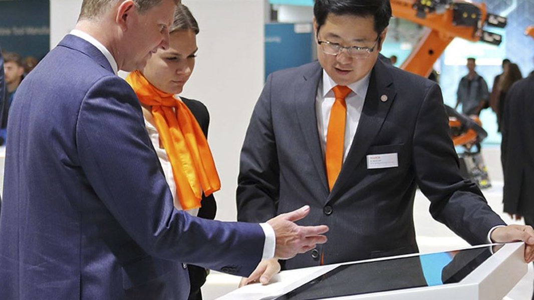 Vertriebsgespräch am Touchtisch auf dem Messestand von KUKA